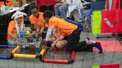 In this Thursday, April 25, 2019 photo, The IronMechs, a middle school team from Haymarket, Va., collaborate in the pit before competition begins at the VEX World Robotics Championships in Louisville, KY.