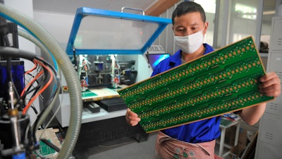 In this May 22, 2018 file photo, a staff member works in a circuit board manufacturing facility in Hangzhou in eastern China's Zhejiang province. In a report issued Monday, May 20, 2019, a business group says the number of foreign companies in China that feel compelled to hand over technology in exchange for market access has doubled since two years ago.