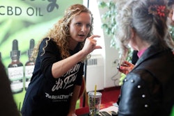 In this April 7, 2019 photo, Lindsey Bouras, left, wellness consultant at The Healthy Place, formerly known as Apple Wellness, talks to an attendee about CBD oil at the, It's Hemp, It's Fine hemp/CBD event, at Monona Terrace Convention Center in Madison, Wisc. The event featured a panel discussion, informational booths, and free samples of CBD coffee, beer, kombucha, candy and more.