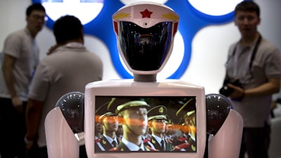 In this Aug. 15, 2018, file photo, a video screen plays footage of Chinese People's Liberation Army (PLA) soldiers on a robot from a Chinese robot maker at the World Robot Conference in Beijing. For four decades, Beijing has cajoled or pressured foreign companies to hand over technology. And its trading partners say if that didn't work, China stole what it wanted.