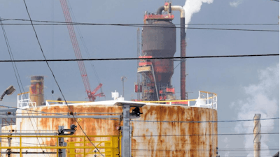 In this Sept. 18, 2009, file photo, a man works at the Exxon Mobil refinery in Baytown, Texas. Exxon Mobil says it plans to spend $2 billion to expand a chemicals plant next to the Houston Ship Channel and that the project will create 2,000 temporary construction jobs. The company said Thursday, May 2, 2019, it will build a new unit at the Baytown plant to make chemical compounds that give plastics more elasticity and flexibility, and produce ingredients used in engine and industrial oils. Exxon says the facility should begin operating in 2022.