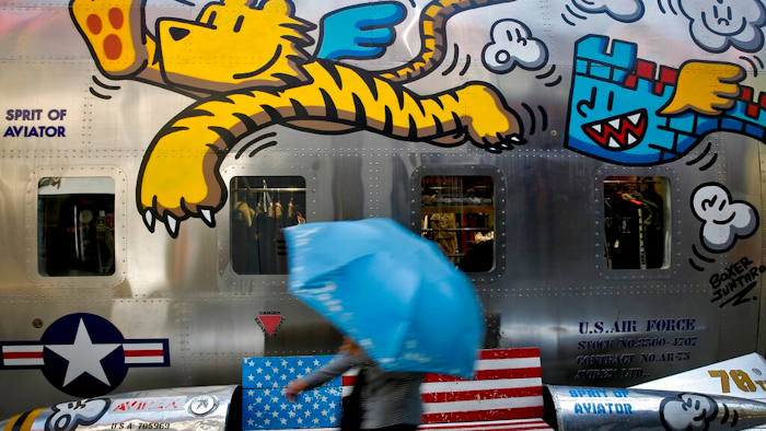 In this May 13, 2019, file photo, a woman walks by a bench painted with an American flag outside a fashion boutique selling U.S. brand clothing at the capital city's popular shopping mall in Beijing. China's Commerce Ministry said Thursday, June 20, 2019, that officials on both sides are preparing for a meeting of Presidents Donald Trump and Xi Jinping in Osaka, but that threats and tariffs will not resolve trade tensions between the two biggest economies.