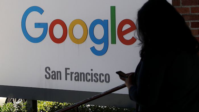 In this May 1, 2019, file photo, a woman walks past a Google sign in San Francisco. The U.S. Justice Department and the Federal Trade Commission are moving to investigate Google, Facebook, Amazon and Apple over their aggressive business practices, and the House Judiciary Committee has announced an antitrust probe of unidentified technology companies.