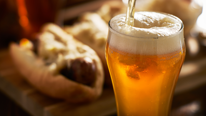 Pouring Amber Beer Into Mug With Bratwursts In Background 843389516 3867x2579
