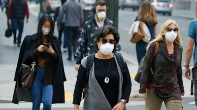 In this Friday, Nov. 9, 2018 file photo, people wear masks while walking through the Financial District in the smoke-filled air in San Francisco, as authorities issued an unhealthy air quality alert for parts of the San Francisco Bay Area as smoke from a massive wildfire drifts south. In 2017 and 2018, the nation had more polluted air days than just a few years earlier, federal data shows. While it remains unclear whether this is the beginning of a trend, health experts say it’s a troubling development.
