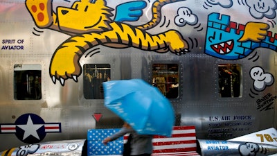 In this May 13, 2019, file photo, a woman walks by a bench painted with an American flag outside a fashion boutique selling U.S. brand clothing at the capital city's popular shopping mall in Beijing. China's Commerce Ministry said Thursday, June 20, 2019, that officials on both sides are preparing for a meeting of Presidents Donald Trump and Xi Jinping in Osaka, but that threats and tariffs will not resolve trade tensions between the two biggest economies.