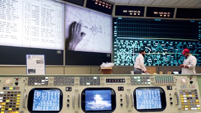 The console for Booster Systems Engineer, the first position on the first row known as 'The Trench,' has an overview of the Display and Projection screens as workers continue restoring the Apollo mission control room to replicate the Apollo mission era 50 years ago at the NASA Johnson Space Center. The screens are displaying, from left, spacecraft telemetry data, the position of astronauts in relation to Lunar Lander while on the moon, and the position of the Command Module as it orbits the moon.