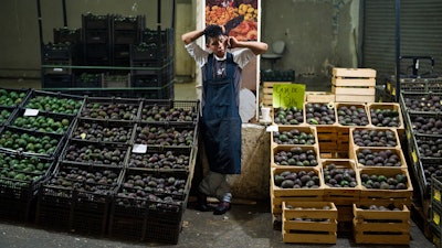 In this file photo, an avocado vendor talks on his cellphone at a market in Mexico City.