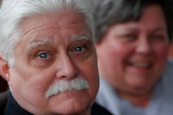 In this April 8, 2019, photo Chuck Pope, left, and wife Nina talk about his ongoing battle with rheumatoid arthritis and trying to afford medications to alleviate the condition while at their home in Derry, Pa. Pope had been battling the disease with an injected drug that his insurance covered while he was still working. It relieves pain and stops irreversible joint damage but retails for over $5,000 a month. Now his Medicare plan doesn't cover that drug, and Pope says his condition is deteriorating without it. Meanwhile, sales of approved, cheaper versions have been blocked.