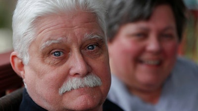 In this April 8, 2019, photo Chuck Pope, left, and wife Nina talk about his ongoing battle with rheumatoid arthritis and trying to afford medications to alleviate the condition while at their home in Derry, Pa. Pope had been battling the disease with an injected drug that his insurance covered while he was still working. It relieves pain and stops irreversible joint damage but retails for over $5,000 a month. Now his Medicare plan doesn't cover that drug, and Pope says his condition is deteriorating without it. Meanwhile, sales of approved, cheaper versions have been blocked.