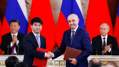 Guo Ping, deputy Chairman of Huawei Technologies Co Ltd, foreground left, shakes hands with Russian President of MTS mobile network operator, Alexei Kornya as Russian President Vladimir Putin, right, and Chinese President Xi Jinping attend a signing ceremony following their talks in the Kremlin in Moscow, Russia, Wednesday, June 5, 2019. Chinese President Xi Jinping is on visit to Russia this week and is expected to attend Russia's main economic conference in St. Petersburg.