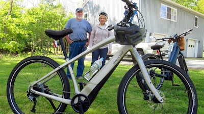 In this June 8, 2019 photo, Gordon and Janice Goodwin show their electric-assist bicycles outside their home in Bar Harbor, Maine. The bikes are banned on carriage roads and bicycle paths in nearby Acadia National Park.