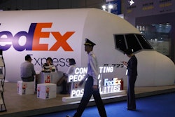 In this Nov. 5, 2018, file photo, a man dressed as a pilot walks past the FedEx booth during the China International Import Expo in Shanghai. China's state media said Saturday, June 1, 2019, that the country is investigating FedEx after it diverted packages sent by Chinese tech giant Huawei.
