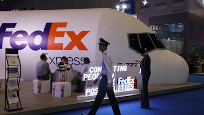 In this Nov. 5, 2018, file photo, a man dressed as a pilot walks past the FedEx booth during the China International Import Expo in Shanghai. China's state media said Saturday, June 1, 2019, that the country is investigating FedEx after it diverted packages sent by Chinese tech giant Huawei.