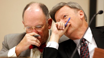 In this Oct. 26, 2009, file pool photo, Larry Leake, right, State Board of Elections Chairman, right, speaks with board member Robert Cordle during board's hearing on in Raleigh, N.C. North Carolina's elections board is delaying a decision on certifying voting-machine makers until learning more about who owns them as worries grow about foreign interference, Dickerson said Friday, June 14, 2019.