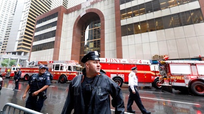 New York City Police and Fire Department personnel secure the scene in front of a building in midtown Manhattan where a helicopter crash landed, Monday, June 10, 2019. The Fire Department says the helicopter crash-landed on the top of the tower, which isn't far from Rockefeller Center and Times Square.