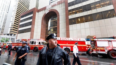 New York City Police and Fire Department personnel secure the scene in front of a building in midtown Manhattan where a helicopter crash landed, Monday, June 10, 2019. The Fire Department says the helicopter crash-landed on the top of the tower, which isn't far from Rockefeller Center and Times Square.