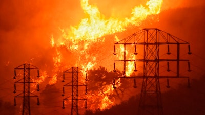 This file photo shows flames burning near power lines in Montecito, California during 2017 wildfires caused by PG&E equipment.