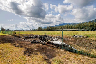 This is the site where a Beechcraft King Air twin-engine plane crashed Friday evening killing multiple people seen on Saturday, June 22, 2019, in Mokuleia, Hawaii. No one aboard survived the skydiving plane crash, which left a small pile of smoky wreckage near the chain link fence surrounding Dillingham Airfield, a one-runway seaside airfield.