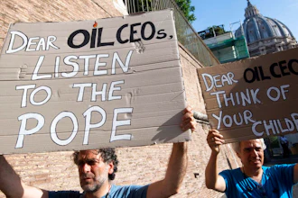 Activists hold up signs outside the Vatican as Pope Francis meets with oil executives, Friday, June 14, 2019. The meeting marked the second year that Francis has invited oil and financial sector executives to the Vatican to impress upon them his concern that preserving God’s creation is one of the fundamental challenges facing humankind today.