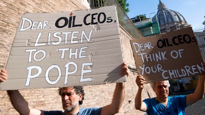 Activists hold up signs outside the Vatican as Pope Francis meets with oil executives, Friday, June 14, 2019. The meeting marked the second year that Francis has invited oil and financial sector executives to the Vatican to impress upon them his concern that preserving God’s creation is one of the fundamental challenges facing humankind today.