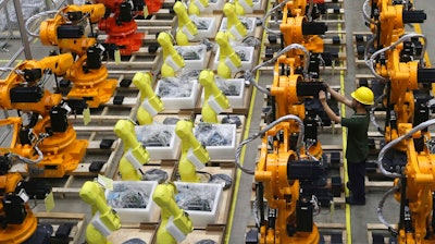 A worker checks on robot arms at a factory in Nanjing in east China's Jiangsu province, Thursday, June 6, 2019. China's Commerce Ministry will release a list of 'unreliable' foreign companies in the near future, a spokesman said Thursday, without giving a specific date. The new list, announced last week, is widely seen as a response to a U.S. decision to put Huawei Technologies on a blacklist for alleged theft of intellectual property and evasion of Iran sanctions.