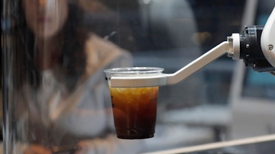 A customer waits for a coffee in front of a robot named b;eat after placing an order at a cafe in Seoul, South Korea.