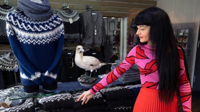 Sales assistant Nuria Medina Marin gestures to a 'lopi' sweater in the Nordic store in Reykjavik. The individually produced, very warm sweaters have become a symbol of Iceland. But increasingly the local wool is being shipped to the cheaper labor market of China.