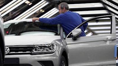 In this Thursday, March 8, 2018 photo an employee works on a Volkswagen car during a final quality control at the Volkswagen plant in Wolfsburg, Germany. Automaker Volkswagen is ruling out compulsory layoffs at its core brand’s German plants for the next 10 years even as it looks for cost cuts and adapts to increasing digitalization.