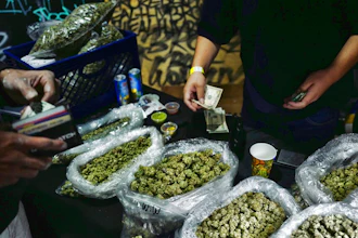 In this April 15, 2019, file photo, a vendor makes change for a marijuana customer at Rev-Up a cannabis marketplace in Los Angeles. An alliance of large cannabis businesses in the growing global marketplace has a message for the public: We're good corporate citizens. The 45-member Global Cannabis Partnership that includes Canopy Growth Corp. and other major companies issued guidelines Tuesday, June 18, 2019, aimed at minimizing greenhouse gas emissions and promoting ethical conduct and responsible pot use.