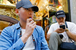 In this Monday, June 17, 2019, photo, Joshua Ni, 24, and Fritz Ramirez, 23, vape from electronic cigarettes in San Francisco. San Francisco supervisors are considering whether to move the city toward becoming the first in the United States to ban all sales of electronic cigarettes in an effort to crack down on youth vaping. The plan would ban the sale and distribution of e-cigarettes, as well as prohibit e-cigarette manufacturing on city property.