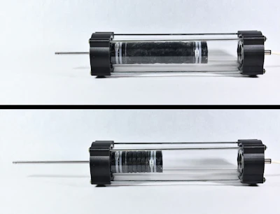 This image shows a prototype of the linear tension piston, rested (on top) and pressurized (on the bottom).