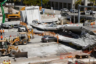 In this March 16, 2018 file photo crushed cars are shown under a section of a collapsed pedestrian bridge near Florida International University in the Miami area. A federal workplace safety agency says engineers had knowledge of extensive cracking and failed to order to close a street and shore up a pedestrian bridge before it collapsed and killed six people at a Miami university last year. On Tuesday, June 11, 2019 a report by the U.S. Occupational Safety and Health Administration concluded the size of the cracks warranted the street be shut down immediately.
