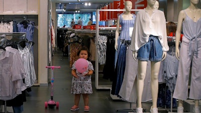 A child plays with a balloon at a clothing store having a promotion sale in Beijing, Monday, July 15, 2019. China's economic growth sank to its lowest level in at least 26 years in the quarter ending in June, adding to pressure on Chinese leaders as they fight a tariff war with Washington.