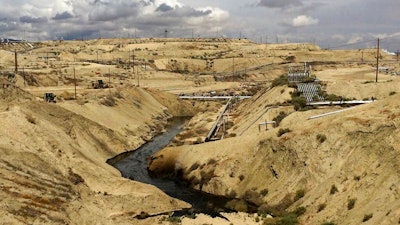 In this May 10, 2019 photo provided by the California Department of Fish and Wildlife's Office of Spill Prevention and Response, oil flows at a Chevron oil field in Kern County, Calif. Nearly 800,000 gallons of oil and water has seeped from the ground since May. Chevron and California officials say the spill is not near any waterway and has not significantly affected wildlife.