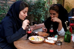 Two Iranians drink Coca-Cola at a cafe in downtown Tehran, Iran, Wednesday, July 10, 2019. Whether at upscale restaurants or corner stores, American brands like Coca-Cola and Pepsi can be seen throughout Iran despite the heightened tensions between the two countries. U.S. sanctions have taken a heavy toll, but Western food, movies, music and clothing are still widely available.