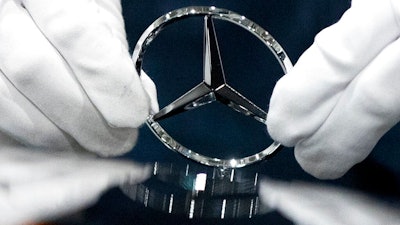 In this file photo dated Wednesday, April 3, 2019, a worker wipes a logo of a car at the Mercedes Benz automobile assembly plant outside Moscow, Russia. German automaker Daimler expects pretax profits this year to be significantly lower than 2018, after setting aside more money to tackle the fallout from its diesel emissions problems and an airbag recall.