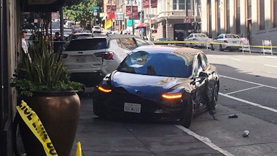 In this Sunday, July 21, 2019 file photo shows the scene after a woman was arrested after running a red light in a rented Tesla in San Francisco and causing a crash that killed a tourist and left his wife critically injured. San Francisco police said Wednesday, July 24, 2019, preliminary information shows a rented Tesla that was speeding when it ran a red light and struck a couple was not on semi-autonomous Autopilot mode.