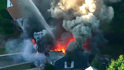 In this Sept. 13, 2018 file image from video provided by WCVB in Boston, flames consume the roof of a home following an explosion in Lawrence, Mass. Columbia Gas of Massachusetts and its parent, NiSource Inc., announced Monday, July 29, 2019, a settlement had been reached in class action lawsuits resulting from the disaster across several towns north of Boston.