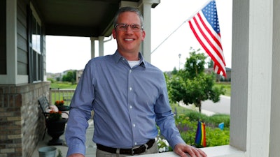 In this Monday, July 1, 2019, photo, software engineer Joe Wilson poses for a photo outside his home in Highlands Ranch, Colo. The tariffs that the Trump administration has placed on thousands of products imported from China and retaliatory duties placed on U.S. goods are affecting many small businesses, even if they’re not importers or exporters. Wilson might have to put off hiring freelancers if he feels the ripple effects of tariffs that his customers must pay.