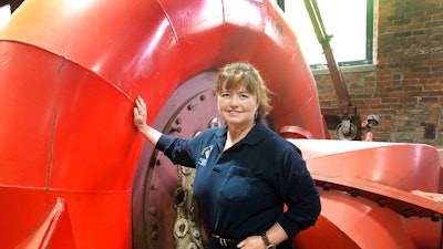 In this June 5, 2019 photo, Natural Power Group co-owner Sarah Bower-Terbush stands in front of a power turbine at the company's hydroelectric site in Wappingers Falls, N.Y. She and her husband sell renewable power to local customers from three hydroelectric sites they operate in the Hudson Valley. Customers say they like investing their money locally in clean power.