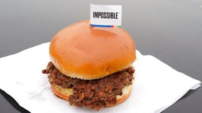 This Jan. 11, 2019, file photo shows the Impossible Burger, a plant-based burger containing wheat protein, coconut oil and potato protein among it's ingredients in Bellevue, Neb. After months of shortages, Impossible Foods is partnering with a veteran food production company to ramp up supplies of its popular plant-based burgers.