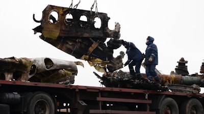 In this file photo dated Sunday, Nov. 16, 2014, recovery workers in rebel-controlled eastern Ukraine load debris from the crash site of Malaysia Airlines Flight 17, in Hrabove, Ukraine, with recovery operations carried out under the supervision of Dutch investigators and officials from the Organization for Security and Cooperation in Europe. Five years after a missile blew Malaysia Airlines Flight 17 out of the sky above eastern Ukraine, relatives and friends of those killed will gather Wednesday July 17, 2019, at a Dutch memorial to mark the anniversary.