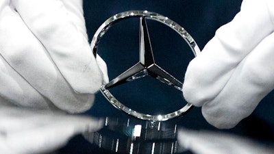 In this file photo dated Wednesday, April 3, 2019, a worker wipes a logo of a car at the Mercedes Benz automobile assembly plant outside Moscow, Russia. German automaker Daimler expects pretax profits this year to be significantly lower than 2018, after setting aside more money to tackle the fallout from its diesel emissions problems and an airbag recall.