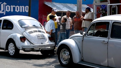 Taxi drivers gather around their Volkswagen Beetles in a neighborhood of Mexico City known colloquially as 'Vocholandia,' for its love of the classic Beetle, called 'vocho', Tuesday, July 9, 2019. Green-and-white painted Beetles used as taxis used to be the norm in Mexico City, but authorities expired the cab licenses for the last of the 'vochos' in in 2012.