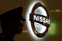 In this Nov. 21, 2018, file photo, a security guard stands near the logo at Nissan Motor Co. Global Headquarters in Yokohama near Tokyo. The executives charged with strengthening governance at Nissan are saying extensive job cuts are coming, designed to drive a recovery at the Japanese automaker.