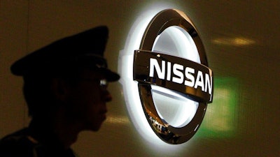 In this Nov. 21, 2018, file photo, a security guard stands near the logo at Nissan Motor Co. Global Headquarters in Yokohama near Tokyo. The executives charged with strengthening governance at Nissan are saying extensive job cuts are coming, designed to drive a recovery at the Japanese automaker.