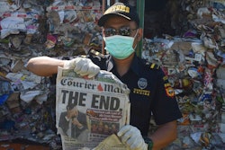 Indonesian custom officers show off the front of a foreign newspaper amoung waste found in a container at the Tanjung Perak port in Surabaya, East Java, Indonesia, Tuesday, July 9, 2019. Indonesia is sending dozens of containers of imported waste back to Western nations after finding it was contaminated with used diapers, plastic and other materials, adding to a growing backlash in Southeast Asia against being a dumping ground for the developed world's rubbish.