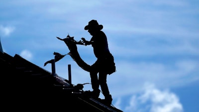 In this July 18, 2019, file photo a roofer works on a new home under construction in Houston. On Wednesday, July 31, the Labor Department reports on wages and benefits for U.S. workers during the April-June quarter.