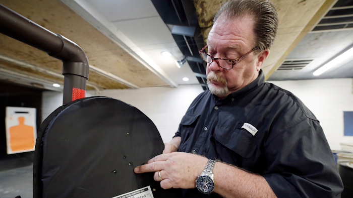 Steve Naremore, founder and CEO of TuffyPacks, shows the impact points on a ballistic shield retrieved from a backpack after a shooting demonstration of the stopping ability of the product.